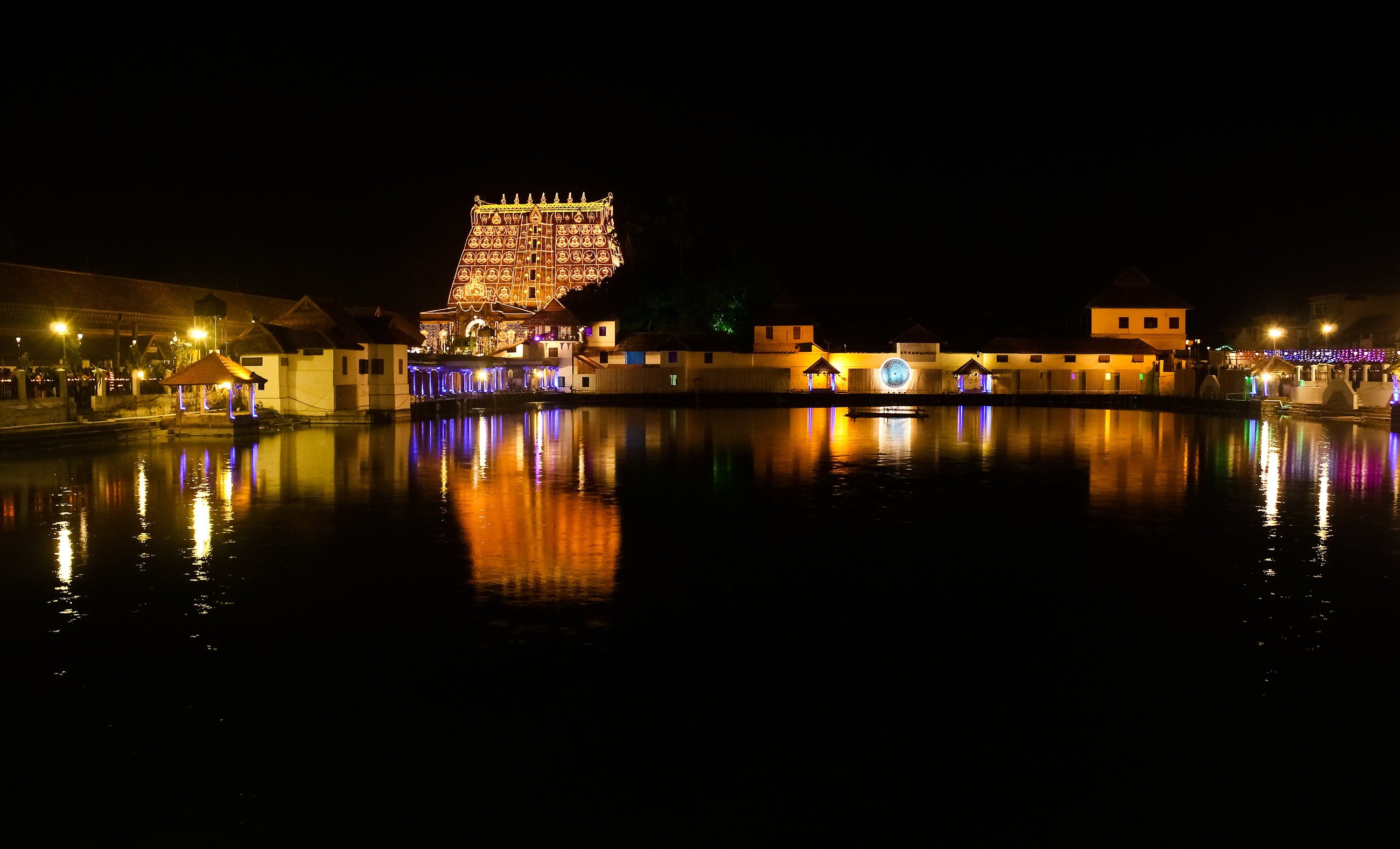 The tower of Sree Padmanabhaswamy Temple lit at night, reflected in the temple tank